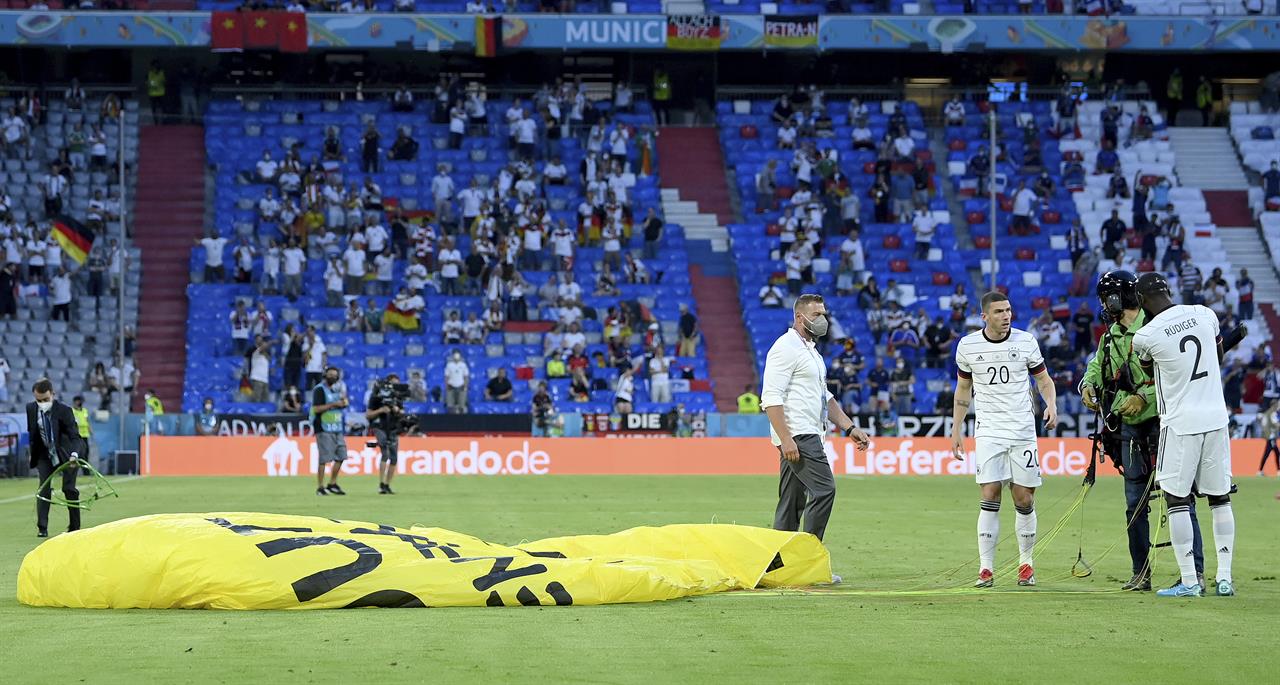 Germany's Antonio Ruediger, right, and Germany's Robin Gosens speak to a protestor who landed on the pitch before the Euro 2020 soccer championship group F match between France and Germany at the Allianz Arena stadium in Munich, Tuesday, June 15, 2021. (Matthias Hangst/Pool via AP)
