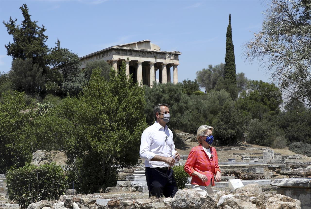 Greek Prime Minister Kyriakos Mitsotakis, left, and European Commission President Ursula von der Leyen, walk in front of the Temple of Hephaestos during an event at the Ancient Agora in Athens, Thursday, June 17, 2021. (Louiza Vradi/Pool via AP)