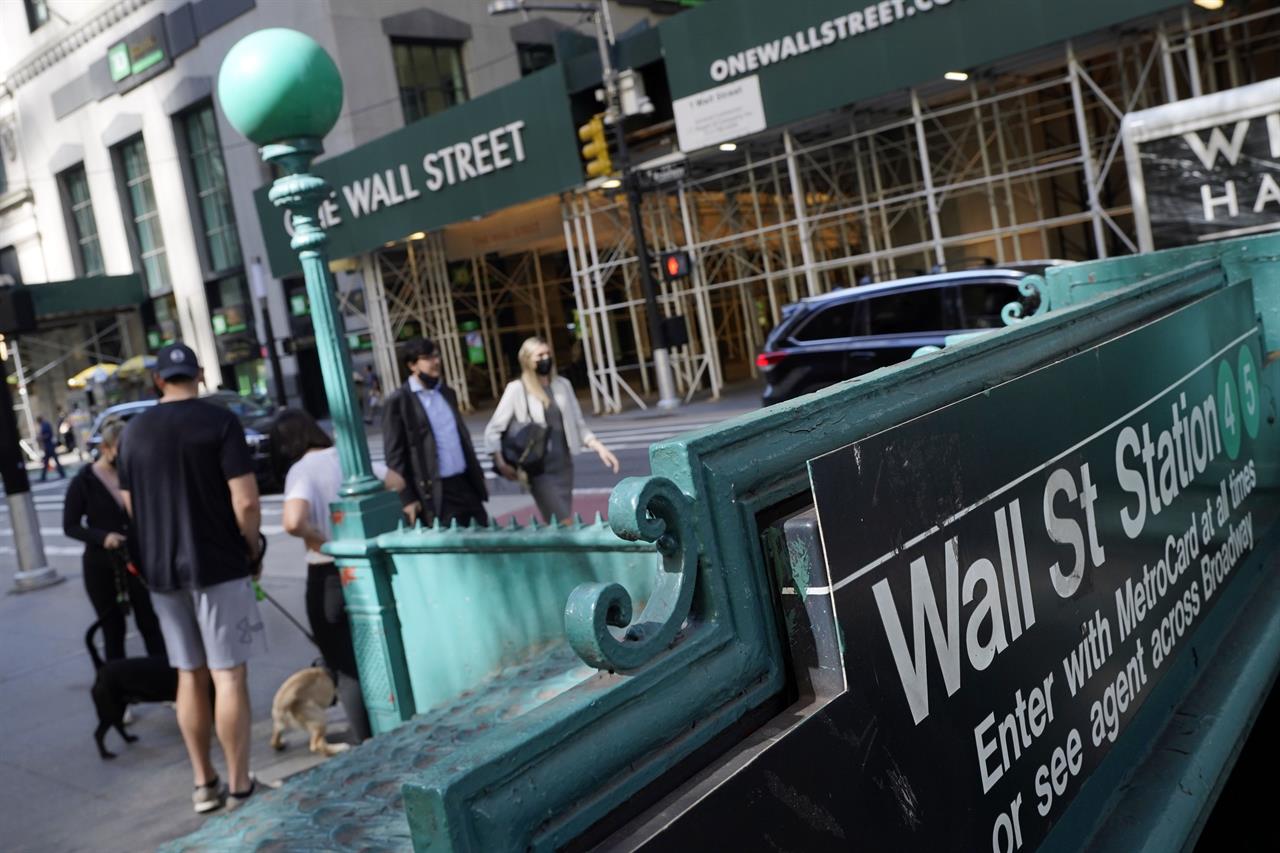 People walk on Broadway at Wall Street, Wednesday, June 16, 2021. Stocks shook off a wobbly start and pushed mostly higher in the first few minutes of trading on Wall Street. The S&P 500 rose 0.1% in the early going Thursday, June 17 and other major indexes were also posting modest gains. (AP Photo/Richard Drew)