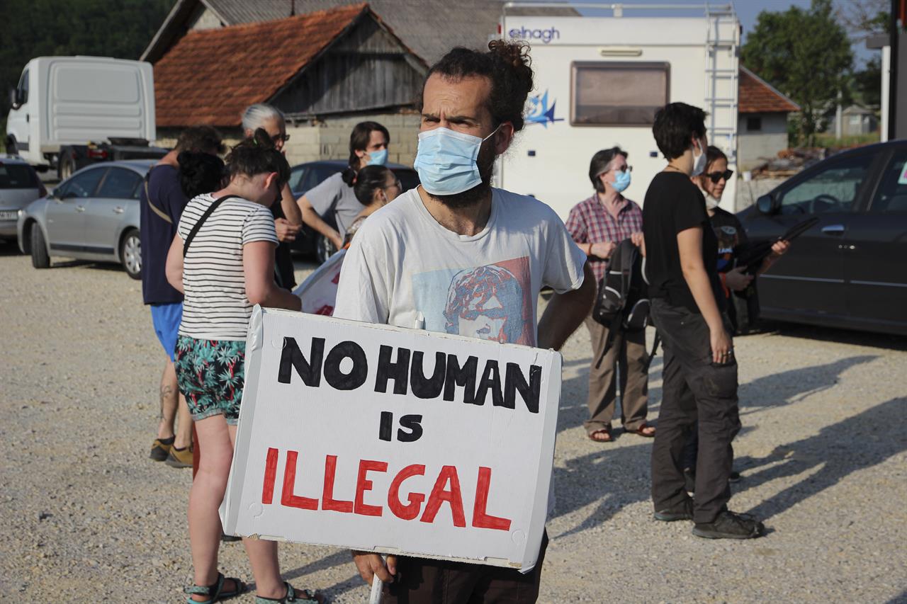 A man holds a banner during a protest against the violent pushbacks of migrants, allegedly conducted by Croatian police, near the border crossing between Croatia and Bosnia Herzegovina in Maljevac, Croatia, Saturday, June 19, 2021. More than one hundred members of human rights NGO's, mostly from Italy, but also from Germany, Austria, Spain and Slovenia blocked the border traffic for about two hours protesting demanding a stop of all deportation of migrants, and cancellation of EU's Frontex operations at borders, preventing migrants from traveling. (AP Photo/Edo Zulic)