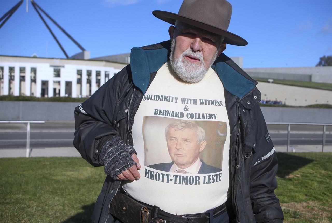 Demonstrator Dierk von Behrens protests outside Parliament House in Canberra, Australia, Thursday, June 17, 2021 against the prosecution of lawyer Bernard Collaery whose picture is on the demonstrator's shirt. Critics of the secret prosecutions of a former Australian spy and his lawyer argue they are another example of a government concealing political embarrassment under the guise of national security. (AP Photo/Rod McGuirk)