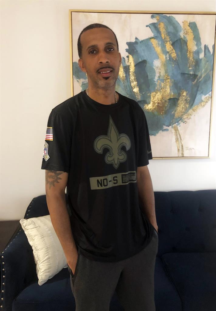 In this photo provided by Angelique Phipps, rapper McKinley "Mac" Phipps stands in his New Orleans home, Wednesday, June 23, 2021, the day after he was released on parole after serving more than 20 years for a 2001 manslaughter conviction in connection with a nightclub shooting in Slidell, Louisiana. The parole for Phipps, who has long maintained he was wrongfully convicted for the shooting, was granted Tuesday. (Angelique Phipps via AP)