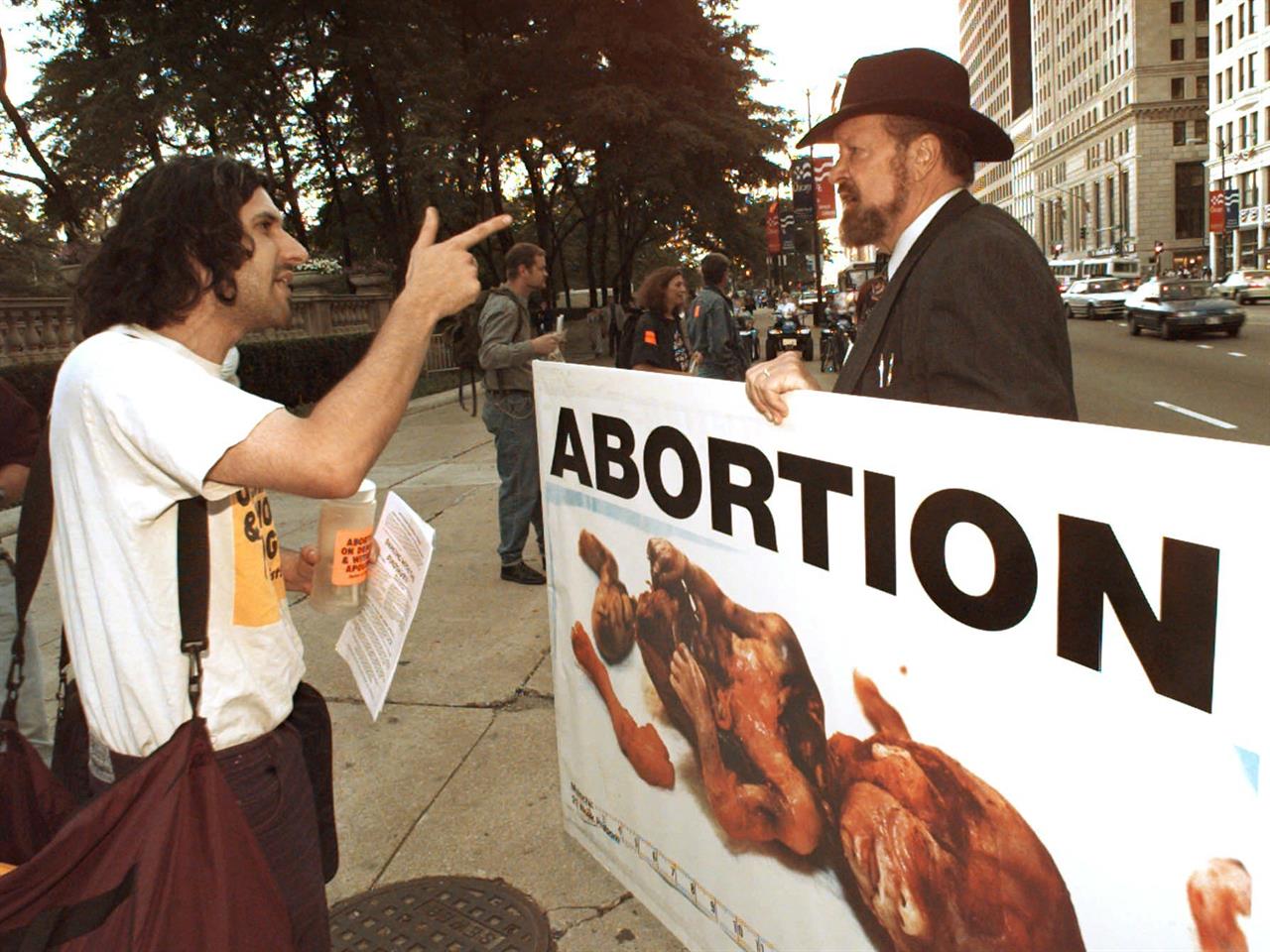 Abortion rights protestor Jay Lynn, left, argues with anti-abortion advocate Joseph Scheidler as he carries a sign along Michigan Ave. in Chicago, Friday, Aug. 23, 1996. Joe Scheidler, the founder of the Pro-Life Action League and prominent figure in the anti-abortion movement, died Monday, Jan. 18, 2021 the organization announced. He was 93. (AP Photo/John Gaps III, file)