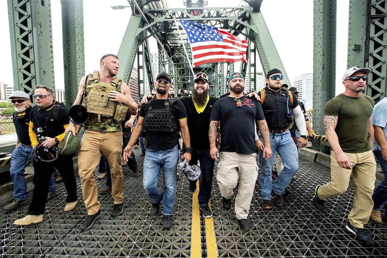 FILE - Members of the Proud Boys, including organizer Joe Biggs, third from right, march across the Hawthorne Bridge during an "End Domestic Terrorism" rally in Portland, Ore., on Saturday, Aug. 17, 2019. Biggs was arrested Wednesday, Jan. 20, 2021 for taking part in the siege of the U.S. Capitol earlier this month, authorities said. Biggs, 37, was arrested in central Florida and faces charges of obstructing an official proceeding before Congress, entering a restricted on the groups of the U.S. Capitol and disorderly conduct. (AP Photo/Noah Berger, file)