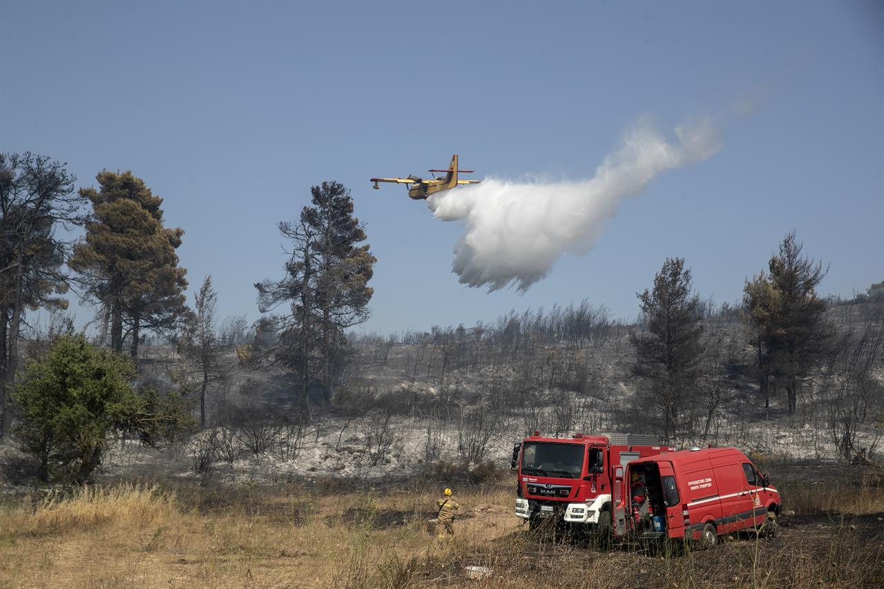 A firefighting airplane drops water during a forest fire at Dionysos northern suburb of Athens, on Tuesday, July 27, 2021. Greek authorities have evacuated several areas north of Athens as a wildfire swept through a hillside forest and threatened homes despite a large operation mounted by firefighters. (AP Photo/Yorgos Karahalis)