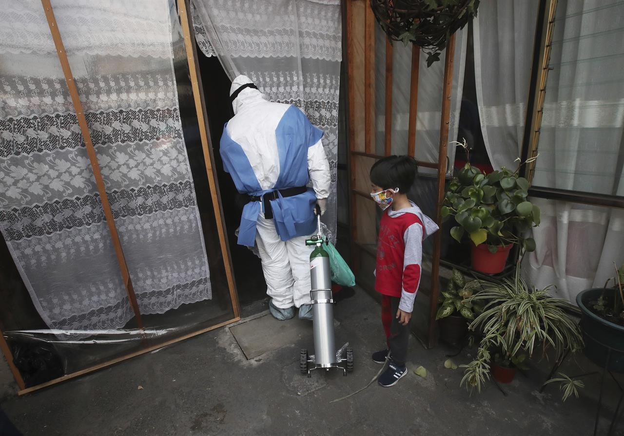City worker Carlos Ruiz delivers a tank of oxygen to a COVID-19 patient, in the Iztapalapa borough of Mexico City, Friday, Jan. 15, 2021. The city offers free oxygen refills for COVID-19 patients. (AP Photo/Marco Ugarte)