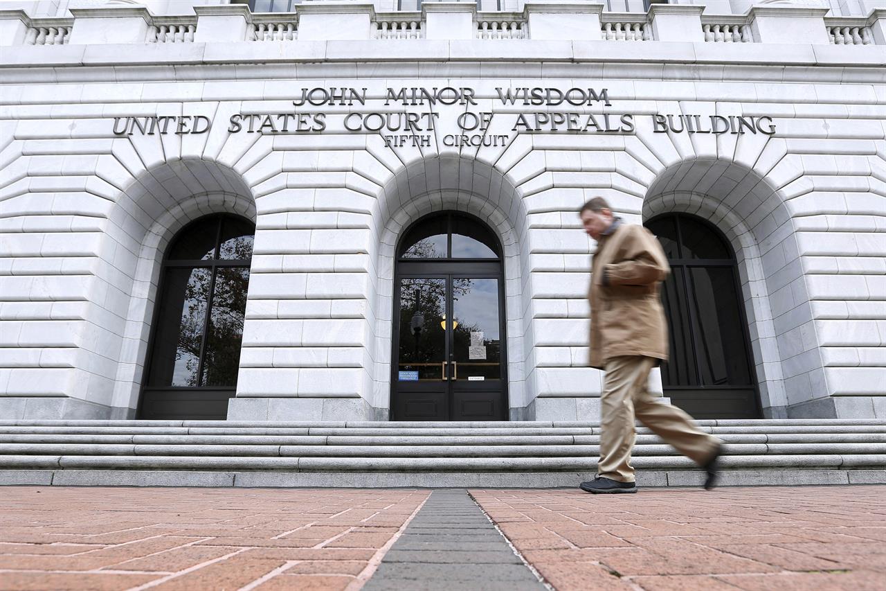 FILE - In this Jan. 7, 2015, file photo, a man walks in front of the 5th U.S. Circuit Court of Appeals in New Orleans. Texas should be allowed to halt a common second-trimester abortion procedure, the state's lawyers told a federal appeals court Thursday, Jan. 21, 2021, in a hearing punctuated by debates over fetal pain and the rights of women to medically safe abortion. (AP Photo/Jonathan Bachman, File)