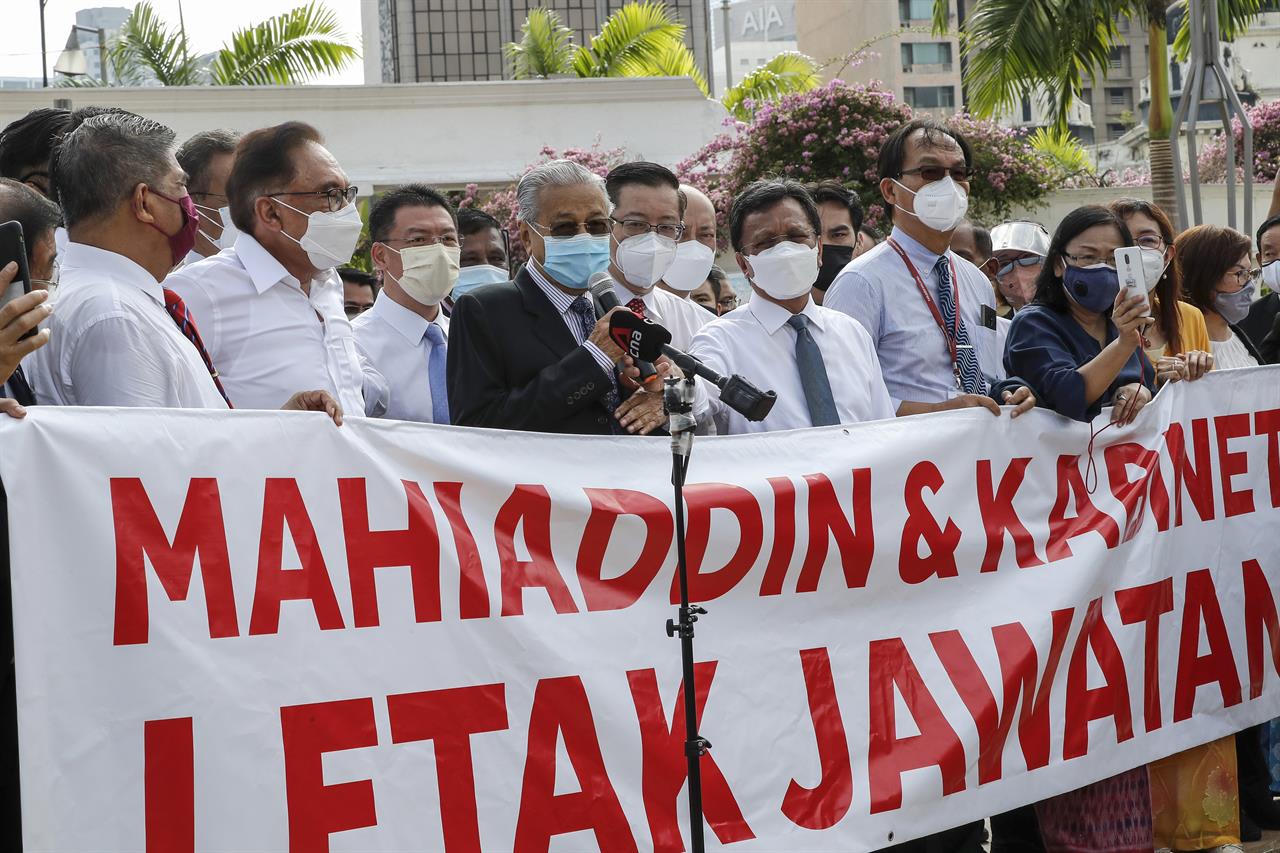 Malaysian opposition members Anwar Ibrahim, third from left, and Mahathir Mohamad, fifth from left, speak to the media during a protest in Kuala Lumpur, Malaysia, Monday, Aug. 2, 2021. Malaysian opposition lawmakers marched toward the parliament building in Kuala Lumpur to demand Prime Minister Muhyiddin Yassin to resign. The banner reads: "Muhyiddin and Cabinet resign." (AP Photo/FL Wong)