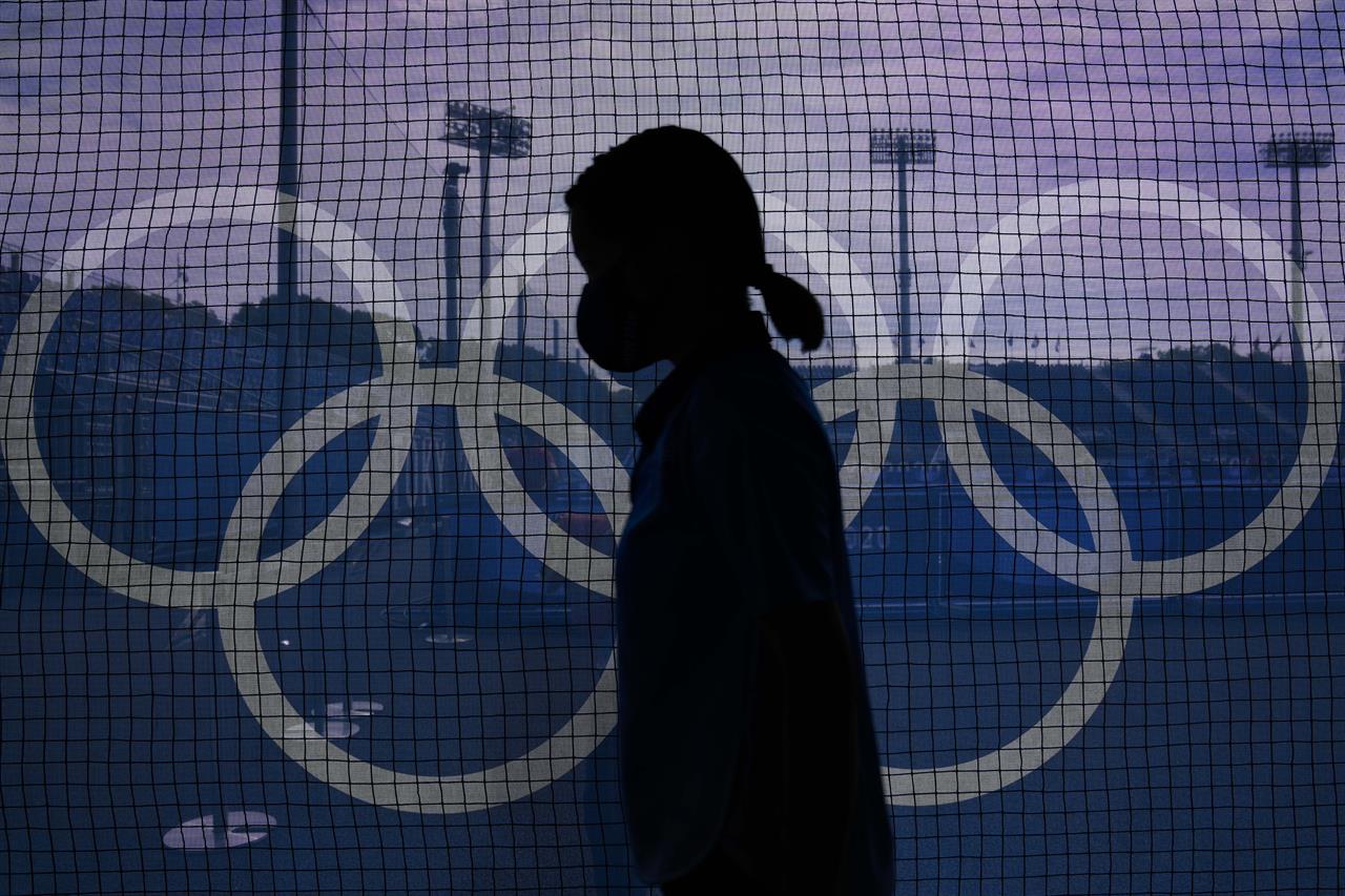 A field attendant passes netting emblazoned with the Olympic rings on the north pitch of Oi Hockey Stadium before a women's field hockey match between Argentina and Germany at the 2020 Summer Olympics, Monday, Aug. 2, 2021, in Tokyo, Japan. (AP Photo/John Locher)