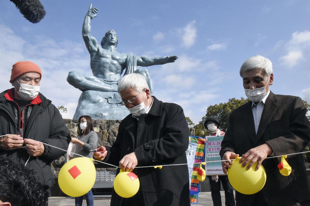 Participants deflate balloons in hope of neutralizing and demolishing nuclear warheads, during a memorial gathering at Peace Park in Nagasaki, southern Japan Friday, Jan. 22, 2021. The first-ever treaty to ban nuclear weapons entered into force on Friday, hailed as a historic step to rid the world of its deadliest weapons but strongly opposed by the world's nuclear-armed nations. (Kyodo News via AP)