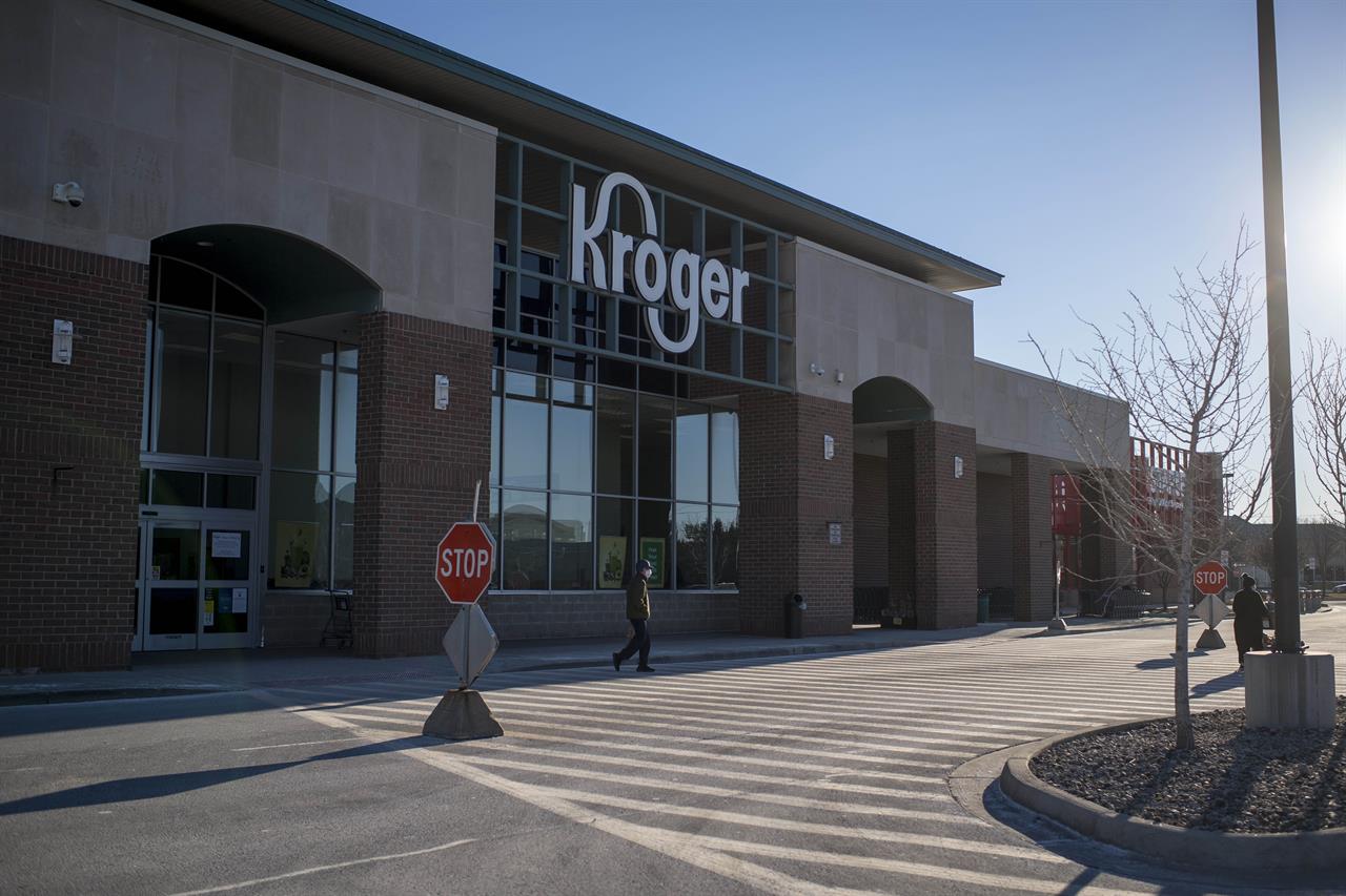 A person walks across the street outside of the Kroger in Novi, Mich on Jan. 23, 2021. A $1 billion winning Mega Millions ticket was sold at the store for the drawing held on Friday, Jan. 22. (Nic Antaya/Detroit News via AP)