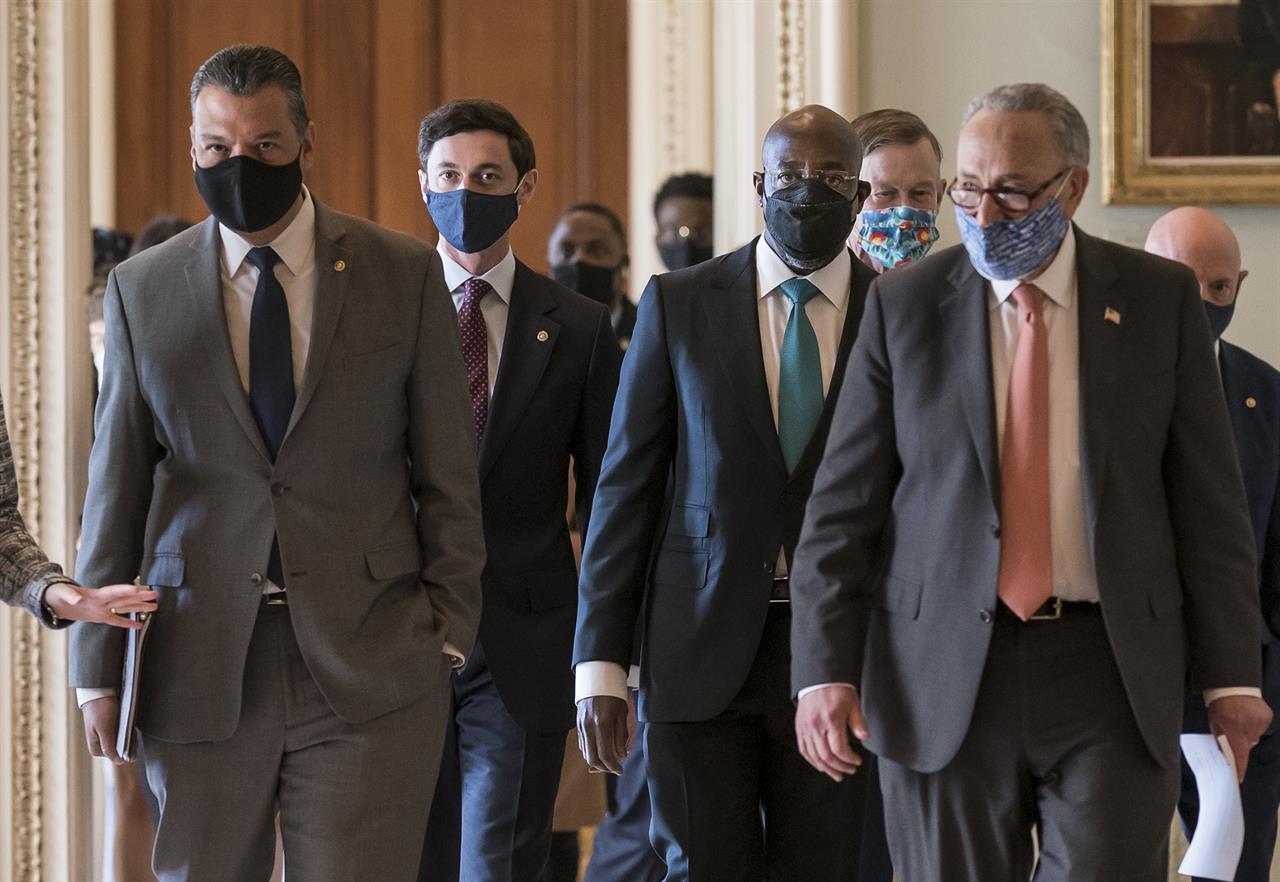 On the first full day of the Democratic majority in the Senate, new members walk to a news conference with Senate Majority Leader Chuck Schumer, D-N.Y., front right, at the Capitol in Washington, Thursday, Jan. 21, 2021. From left are, Sen. Alex Padilla, D-Calif., who took the seat vacated by Vice President Kamala Harris, Sen. Jon Ossoff, D-Ga., Sen. Raphael Warnock, D-Ga., Sen. John Hickenlooper, D-Colo., Sen. Chuck Schumer, D-N.Y., and Sen. Mark Kelly, D-Ariz. (AP Photo/J. Scott Applewhite)