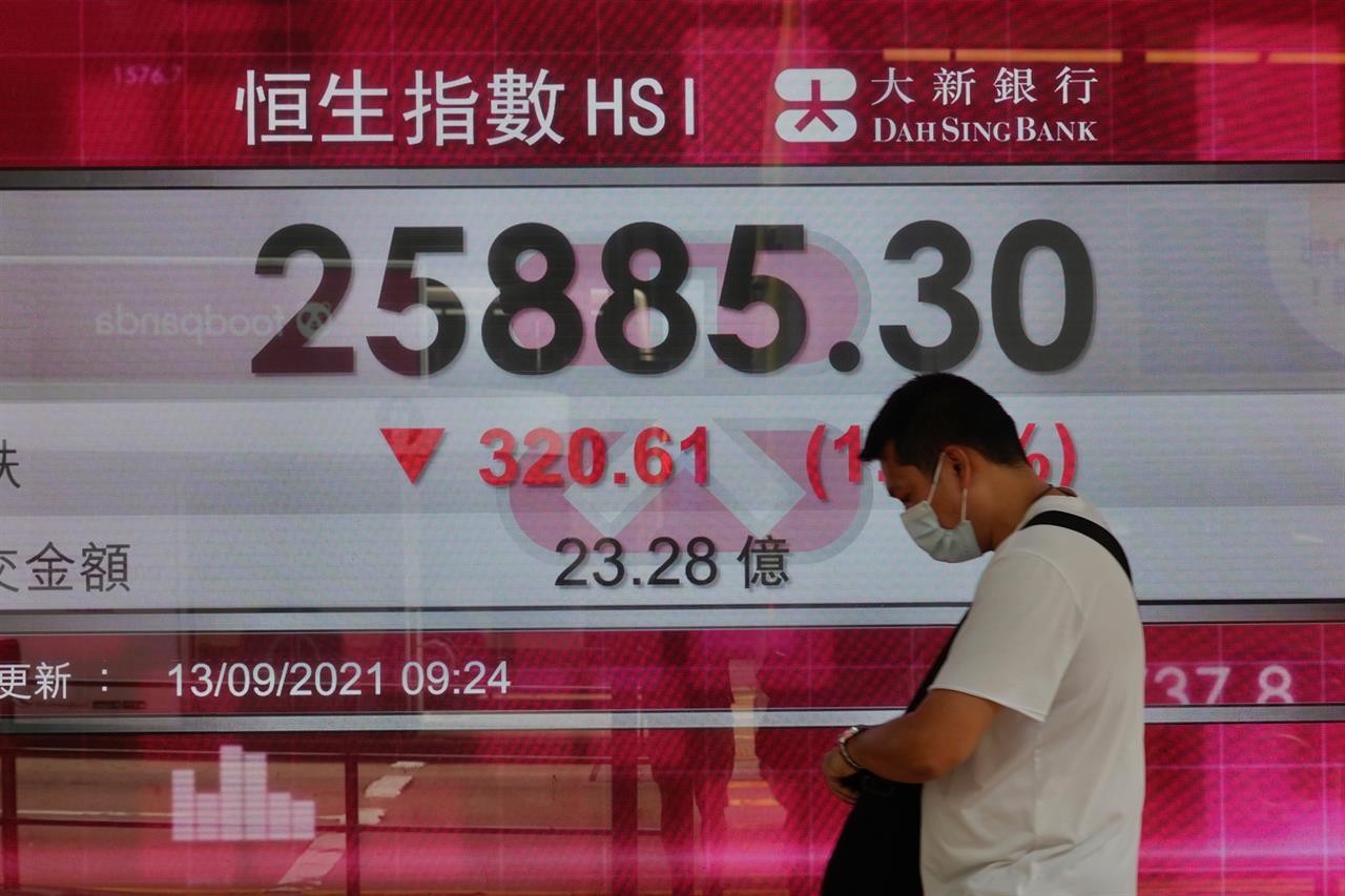 A man walks past a bank's electronic board showing the Hong Kong share index at Hong Kong Stock Exchange in Hong Kong Monday, Sept. 13, 2021. Shares slipped Monday in most Asian markets after Wall Street benchmarks ended last week with a decline. (AP Photo/Vincent Yu)