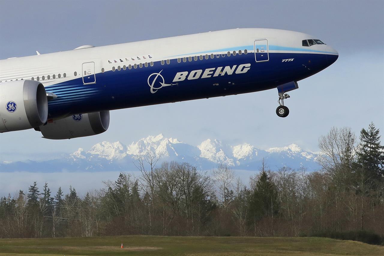 FILE - In this Jan. 25, 2020, file photo a Boeing 777X airplane takes off on its first flight with the Olympic Mountains in the background at Paine Field in Everett, Wash. Boeing is reporting another huge loss, this one because of a setback to its 777X widebody jetliner. Boeing said Wednesday, Jan. 27, 2021, it lost $8.4 billion in the fourth quarter on weaker demand for planes during the pandemic. (AP Photo/Ted S. Warren, File)