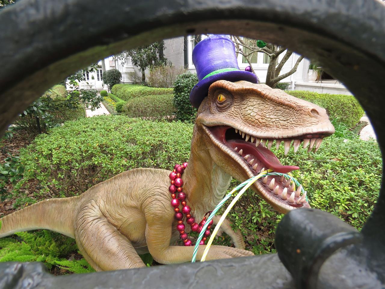 A top-hatted dinosaur, shown Tuesday, Jan. 26, 2021, is among Mardi Gras decorations in the yard of a mansion on St. Charles Avenue in New Orleans. Because pandemic dangers from large and widespread crowds have canceled Mardi Gras parades in New Orleans this year, thousands of people are decorating their homes as floats. (AP Photo/Janet McConnaughey)
