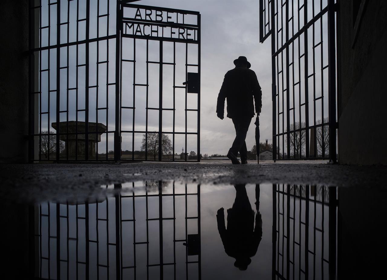 File - In this Sunday, Jan. 27, 2019 file photo, a man walks through the gate of the Sachsenhausen Nazi death camp with the phrase 'Arbeit macht frei' (work sets you free) during International Holocaust Remembrance Day in Oranienburg, about 30 kilometers (18 miles), north of Berlin, Germany. Hundreds of Holocaust survivors in Austria and Slovakia are getting vaccinated against the coronavirus exactly 76 years after the liberation of the Nazi's Auschwitz death camp. More than 400 Austrian survivors were invited to get the vaccine at Vienna's biggest mass vaccination center on International Holocaust Remembrance Day on Wednesday Jan. 27, 2021. (AP Photo/Markus Schreiber, file)