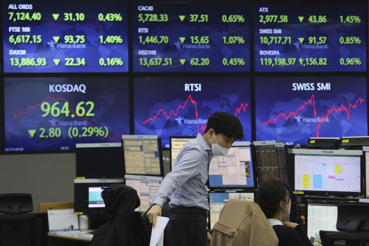 A currency trader talks with his colleague at the foreign exchange dealing room of the KEB Hana Bank headquarters in Seoul, South Korea, Friday, Feb. 19, 2021. Asian stock markets followed Wall Street lower on Friday after disappointing U.S. jobs and economic data. (AP Photo/Ahn Young-joon)