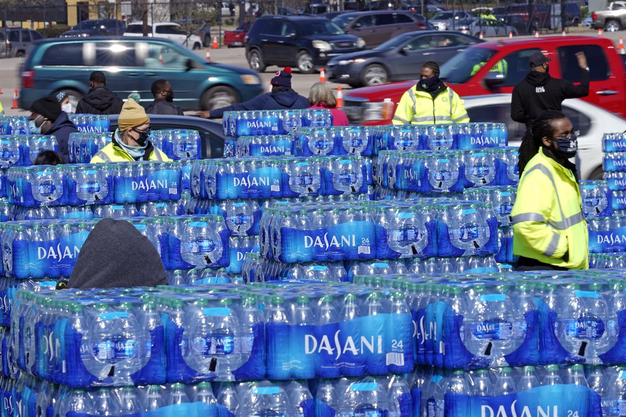 FILE - In this Feb. 19, 2021, file photo, water is loaded into cars at a City of Houston water distribution site in Houston. The drive-thru stadium location was setup to provide bottled water to individuals who need water while the city remains on a boil water notice or because they lack water at home due to frozen or broken pipes. (AP Photo/David J. Phillip, File)