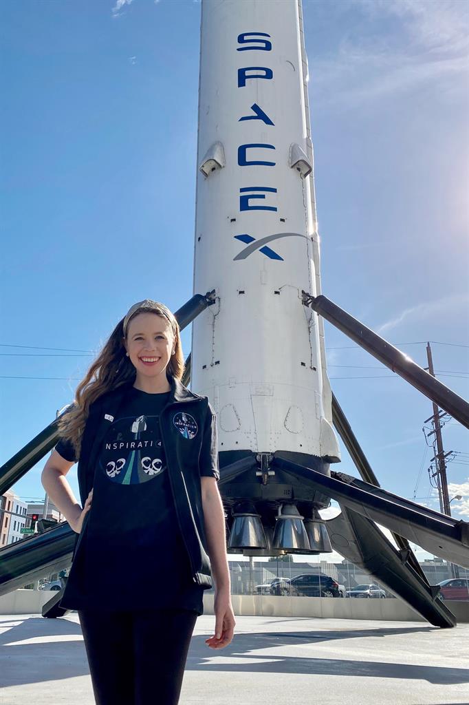 In this undated photo provided by St. Jude Children’s Research Hospital, Hayley Arceneaux stands near a SpaceX rocket at the aerospace company's headquarters in Hawthorne, Calif. Arceneaux, 29, will become the youngest American in space when she blasts off in SpaceX's first private spaceflight planned for the fall of 2021 with entrepreneur Jared Isaacman and two yet-to-be-chosen contest winners. (St. Jude Children’s Research Hospital via AP)