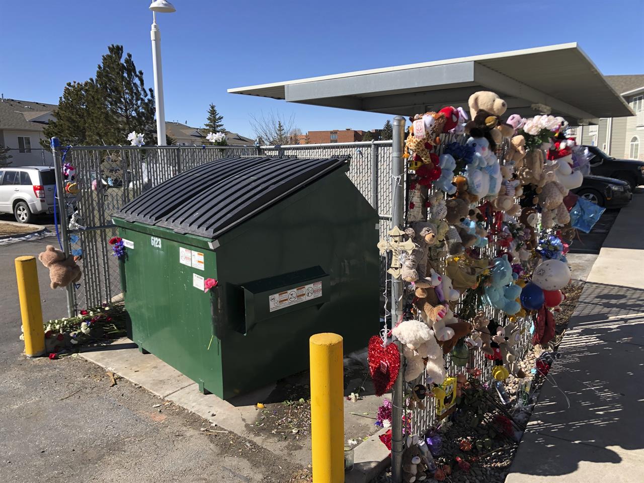 Stuffed animals and notes of condolences are seen attached to a fence Monday, Feb. 22, 2021, around a dumpster at a Cheyenne, Wyo., apartment complex where a 2-year-old boy was found dead. The toddler's body was found in a dumpster several hours after he was reported missing Friday, Feb. 19. (AP Photo/Mead Gruver)