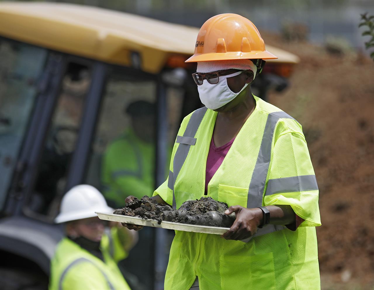 FILE - In this July 21, 2020, file photo, forensic anthropologist Phoebe Stubblefield carries a tray of items found at Oaklawn Cemetery during a test excavation in the search for possible mass graves from the 1921 Tulsa Race Massacre in Tulsa, Okla. A committee overseeing the search for potential mass graves of 1921 Tulsa Race Massacre victims has delayed until next month a decision on how to reinter the remains of possible victims found last year. (Mike Simons/Tulsa World via AP, File)