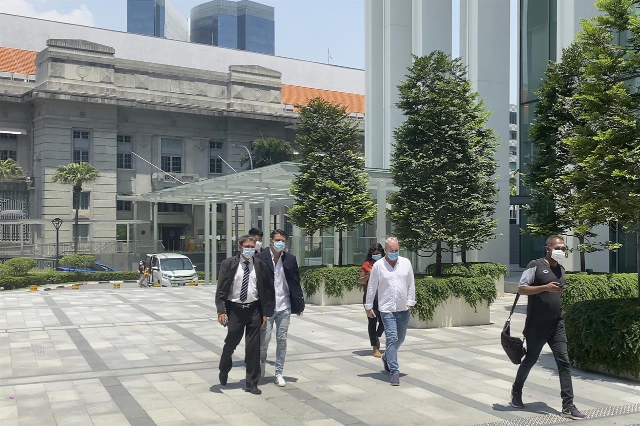 British citizen Nigel Skea, second right, and his defense lawyer Agatha Maghesh Eyamalai, left, walk into the State Courts in Singapore, Friday, Feb. 26, 2021. The Briton man was sentenced to two weeks in jail and fined 1,000 Singapore dollars ($753) for breaking a coronavirus quarantine order in Singapore. (AP Photo/Annabelle Liang)