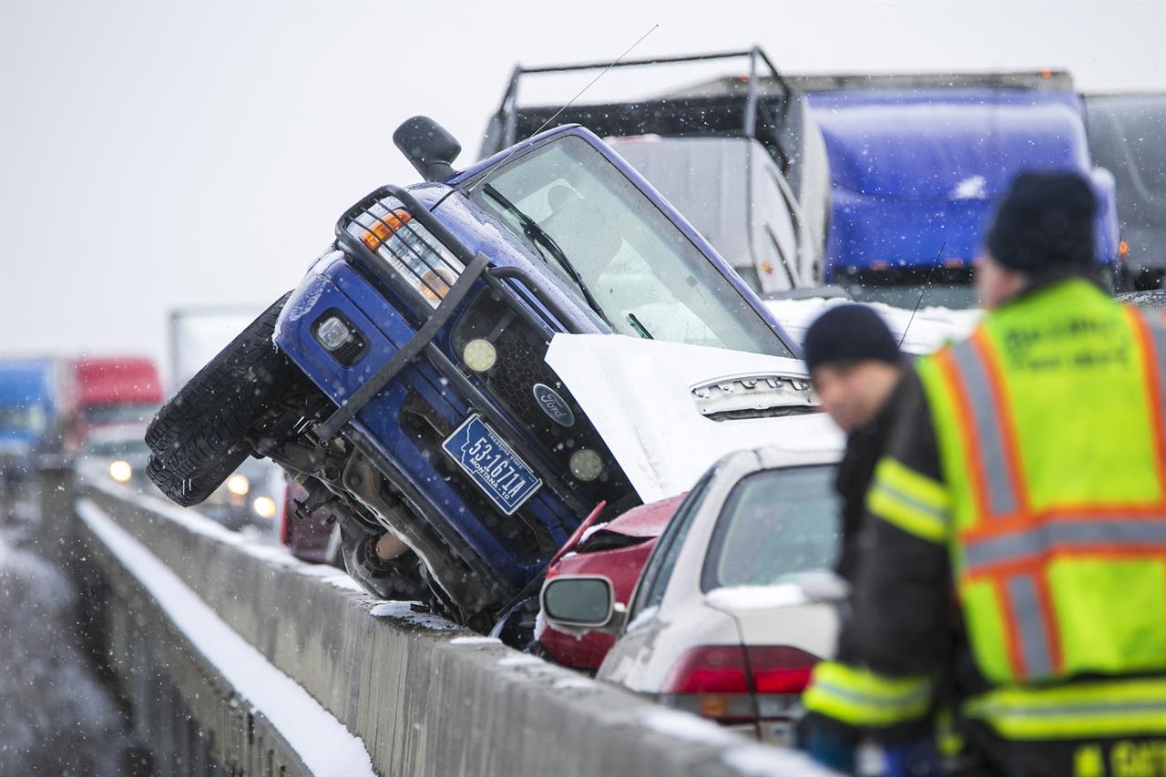 A vehicle leans the edge of the Yellowstone Bridge at the scene of a massive pileup that occurred on I-90 westbound Saturday, Feb. 27, 2021, on the Yellowstone Bridge near Lockwood, Mont. Dozens of vehicles crashed into each other Saturday on an icy interstate highway bridge over the Yellowstone River outside Billings, Montana, making the span appear like a wrecking yard with mashed cars and trucks.(Ryan Berry/The Billings Gazette via AP)