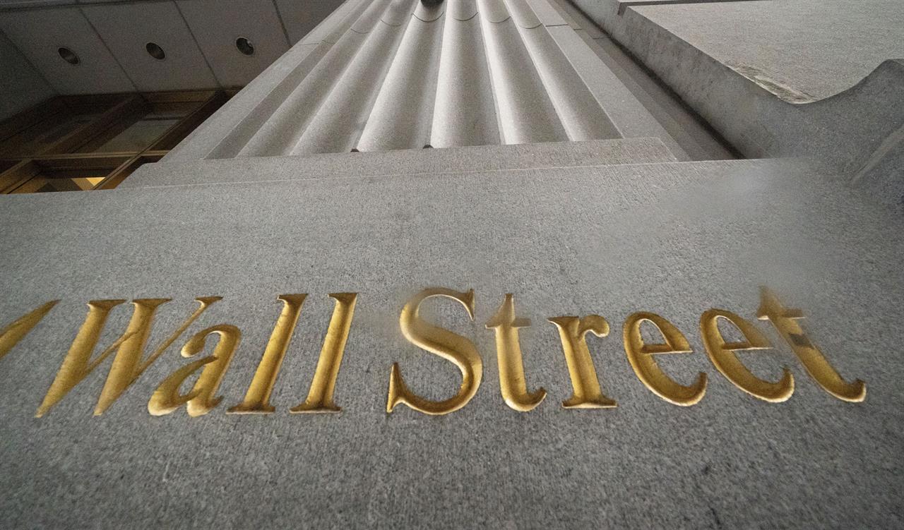 FILE - In this Nov. 5, 2020 file photo, a sign for Wall Street is carved in the side of a building. Investors hit the pause button a day after the biggest market rally in nine months, leaving major indexes little changed in the first few minutes of trading. The S&P 500 slipped a bit less than 0.1% in the early going Tuesday, March 2, 2021. (AP Photo/Mark Lennihan, File)