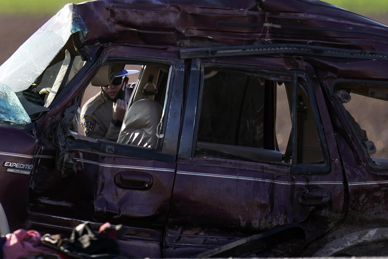 A California Highway Patrol officer examines the scene of a deadly crash in Holtville, Calif., Tuesday, March 2, 2021. Authorities say a semitruck crashed into an SUV, killing multiple people. (AP Photo/Gregory Bull)