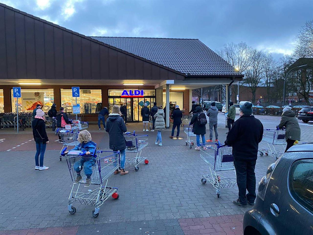 Customers wait for the opening of a branch of the German discounter 'Aldi' in Hamburg, Germany, Saturday, March 6, 2021. From Saturday the discounter offers new coronavirus, COVID-19, quick tests for sale. (Haller/dpa via AP)