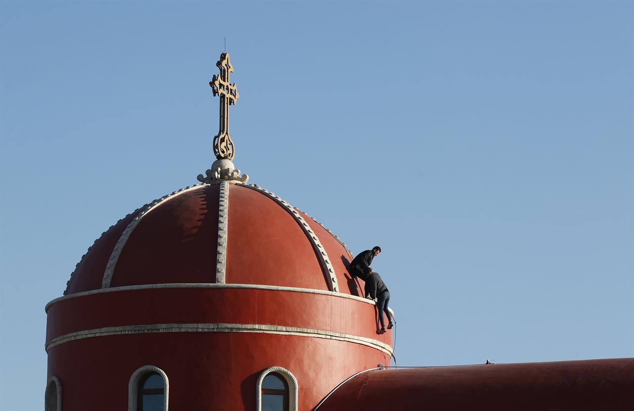 Iraqi Christians clean the the roof of the Church of the Immaculate Conception in Qaraqosh, Iraq, Tuesday, Feb. 23, 2021. Pope Francis will visit the church during his historic trip to Iraq. Damaged during the Islamic State reign of terror, the church's tragedy mirrored that of its Christian community which was devastated by the group. (AP Photo/Hadi Mizban)
