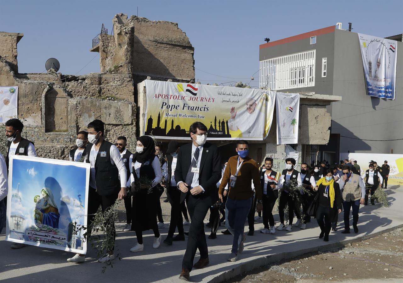Surrounded by shells of destroyed buildings people arrive to join Pope Francis who will pray for the victims of war at Hosh al-Bieaa Church Square, in Mosul, Iraq, once the de-facto capital of IS, Sunday, March 7, 2021. The long 2014-2017 war to drive IS out left ransacked homes and charred or pulverized buildings around the north of Iraq, all sites Francis visited on Sunday. (AP Photo/Andrew Medichini)