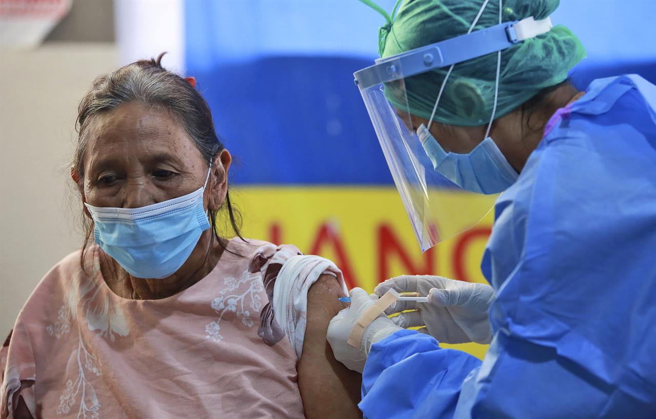A woman receives a shot of China's Sinovac COVID-19 vaccine during a mass vaccination for people above the age of 60 at Adam Malik Hospital in Medan, North Sumatra, Indonesia, Monday, March 8, 2021. The world's fourth most populous country plans to vaccinate two-thirds of its population of about 270 million people, or just over 180 million people in a campaign that is expected to be completed in the first quarter of 2022. (AP Photo/Binsar Bakkara)