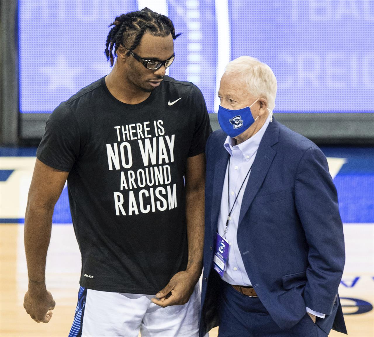 In this March 6, 2021, photo, Creighton's Denzel Mahoney, left, talks to Creighton athletic director Bruce Rasmussen during Senior Day festivities, in Omaha, Neb. Creighton announced Monday, March 8, 2021, it has lifted Greg McDermott's suspension for making racially insensitive remarks to his players after a game last week. Noting McDermott's public apologies and difficult discussions with his players and others, Rasmussen said the coach has shown a willingness to learn from the mistake. (Chris Machian/Omaha World-Herald via AP)