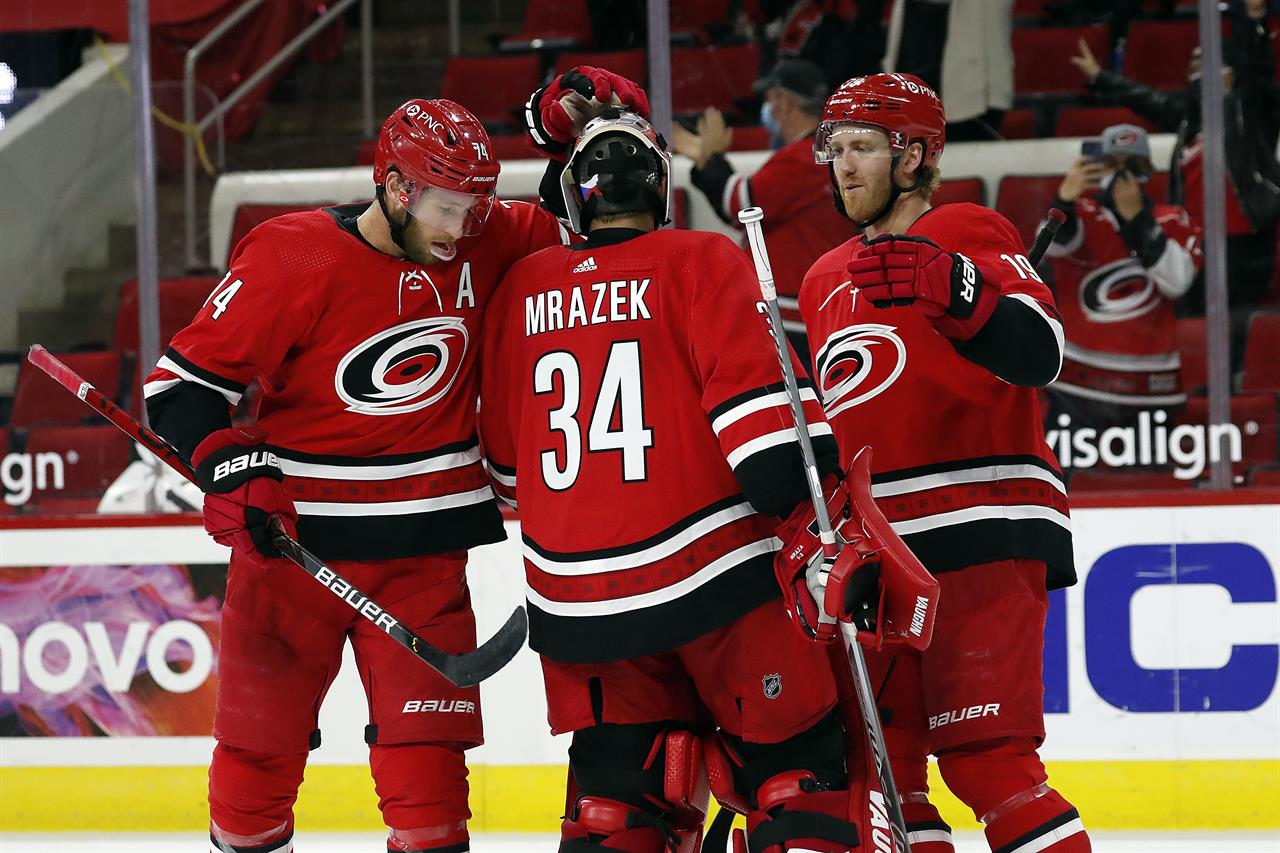 Carolina Hurricanes' Jaccob Slavin (74) and Dougie Hamilton (19) congratulate goaltender Petr Mrazek (34) following the Hurricanes 5-2 win over the Florida Panthers at an NHL hockey game in Raleigh, N.C., Tuesday, April 6, 2021. (AP Photo/Karl B DeBlaker)